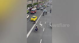 Kind traffic cop holds up motorists on busy road to walk stray dog to safety in Thailand