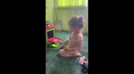 The girl demonstrates how she doesn't like to cook in a toy kitchen