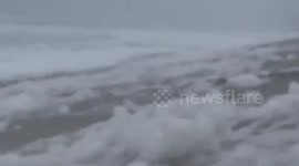 Approaching Nicole’s storm surge whips up sea foam along Florida coast