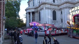 Londoners enjoy amusement rides outside St Pauls Cathedral with Lord Mayors Show underway in the City of London