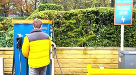 Man operating an EV electric vehicle charging station run by Osprey on the Shell Recharge Network in Leeds, UK.