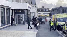 Man led out of asylum seeker hotel by emergency service worker in hazmat suit