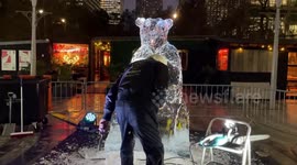 An artist sculpts a bear in the ice during Winter Ice Festival at Canary Wharf