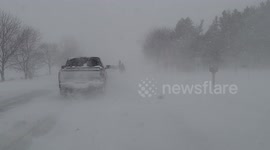 Cars drive slowly behind Amish horse and cart rider during whiteout blizzard in Ontario, Canada