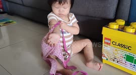 Funny one-year-old toddler tries to put on bra