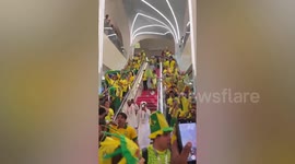 Yellow wave of celebrating Brazil supporters stream down escalator in Qatar