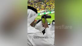 Qatari football fan uses smartphone while zooming through binoculars