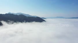 Sea of clouds flows through mountain range in China
