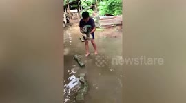 Cute pet Shih Tzu paddles in air as amused owner carries him across flooded street