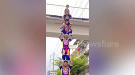 Cute little girl stands on top of amazing human acrobatic tower during parade in Thailand