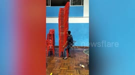Ping pong player carries dozens of chairs on his shoulders to clean up after match