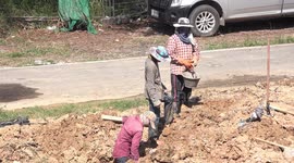 Teamwork on a building site in Thailand, construction workers drain water from a site using a bucket passed from one to the other.