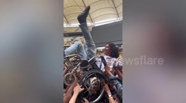 Heartwarming moment friends and party-goers lift young man in wheelchair during rock concert
