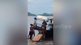 Villagers struggle to load modified motorcycle onto boat in Thailand