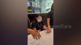 Blindfolded worker names cocktail glasses by touching in unique Christmas party game