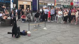 Gutsy street performer attempts to go under a low limbo bar while avoiding the sharp nails under it