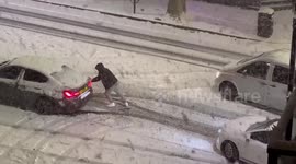 Man pushes his car trapped in London's snow
