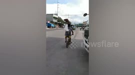 Skilled cyclist carries wooden beam on his head while biking