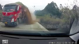 Car narrowly avoids being buried by sand transported on truck after tyre explodes