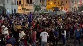 Huge numbers of protesters march through Central Lima, with a group playing drums / flutes