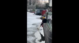 Boaters breaking ice in frozen canal to see how thick it is