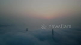 Suspension bridge draped by thick fog clouds in southwest China