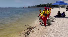 Street cleaners pick up rubbish from artificial beach in the Philippines