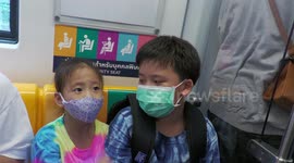 Cute Thai Kids on Bangkok Skytrain wearing masks spot my camera  then whisper