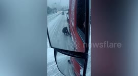 Good young fellow place grass under truck wheel to help it drive uphill in snow