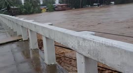 Swollen river threatens to submerge bridge as Christmas floods kill 13 in the Philippines