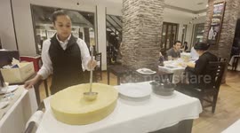 Waitress serves delicious pasta from flaming parmesan cheese wheel