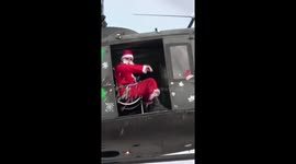 Airborne Santa flying in a military helicopter and delivers candies to kids from the sky