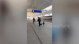Helpful little boy carries plastic bag with father at train station in Laos