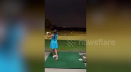 Talented little girl hits golf balls perfectly with driver at practice range
