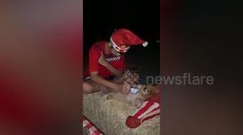 Little boy wearing Santa hat uses dozy pet pooch as phone holder