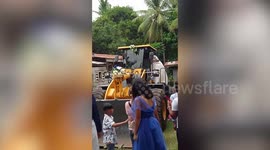Wedding entourage rides backhoe loader to cross muddy track to church in the Philippines