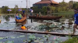 Villagers ride bike along wooden plank over lake