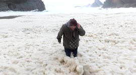 Sea foam covers beach