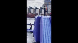 Girl goes SPLASHING into the water after botching jump off inflatable water park