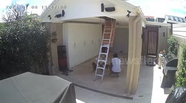 Video of a man petting a dog stands up and whacks his head on the ladder to the attic above.