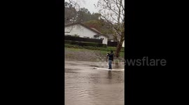 California resident makes most of flooding by paddleboarding through submerged street