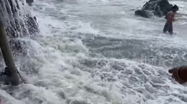 Tourist knocked over by huge wave while posing for pictures on beach
