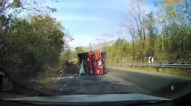 Overloaded truck topples over almost crushing motorcycle rider