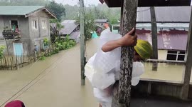 Resident rescued from roof during floods that have killed 10 people in the Philippines