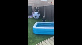 Dad knocks son into pool by kicking a GIANT football his way