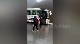 Passengers hold hands to get off bus stranded on icy road