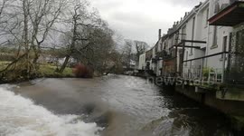 Raging River Ehen flowing past houses in Egremont, Cumbria following torrential rain