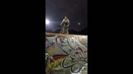 A BMX rider attempts to foot jam a shopping cart that was left at a skatepark and falls off into the stairs