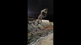 A BMX Rider puts a shopping cart next to a skatepark ramp and successfully foot jams it (balance foot on front tyre and jump back into the ramp)