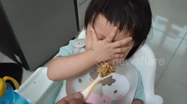 Funny toddler, not impressed by food, covers her face with hand